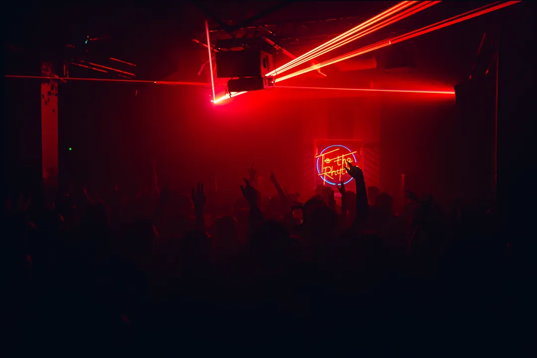 Red lasers over a packed club floor, event photography by Party Pixel